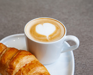 Latte art hot coffee with fresh baked butter croissant