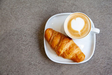 Latte art hot coffee with fresh baked butter croissant