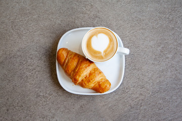 Latte art hot coffee with fresh baked butter croissant