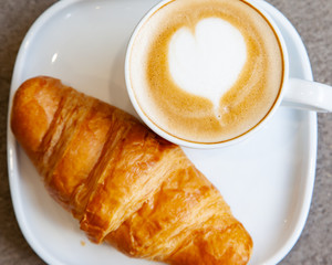 Latte art hot coffee with fresh baked butter croissant