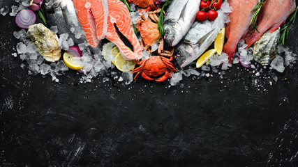 Seafood: Dorado, salmon, crab, grouper, oysters. On a black stone background. Top view. Free space...