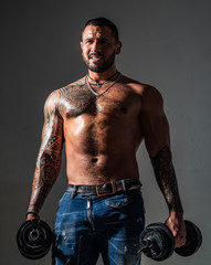 Fototapeta na wymiar Portrait of confident man with beard and tattoo. Power. Lifestyle people concept. Attractive brutal tattooed bearded guy poses with dumbbells. Bearded man. Isolated grey background.