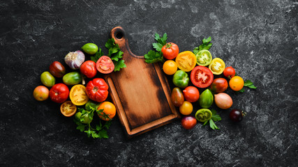 Vegetables. Fresh colored tomatoes On a black stone background. Top view. Free space for your text.