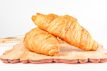 croissants with dry wheat on a wooden board on a white background