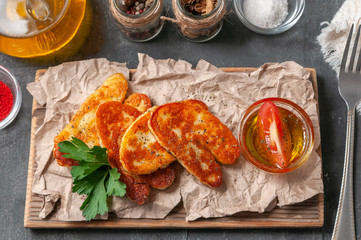 Sliced ​​halumi cheese with spices. On a wooden board. Decorated with spices and parsley. Next to the cheese are cups with olive oil, paprika, salt and spices. View from above. Gray background