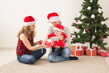 Happy couple with baby celebrating Christmas together at home.