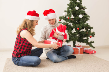 Holidays, children and family concept - Happy couple with baby celebrating Christmas together at home.