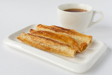 Fried pancakes roll into a tube on a white plate with a white background.