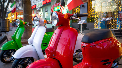 Retro vintage scooters stand near an Italian restaurant. Modern personal transport.