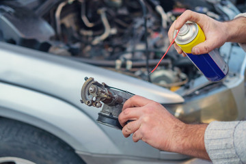 Hands cleaning a detail of a car's engine