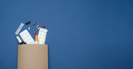 Pharmacy and drugstore online concept. Medicine pills in a paper bag on blue background, space for text