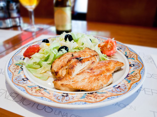 Grilled salmon with spring vegetables on plate, soft focus. Wooden table