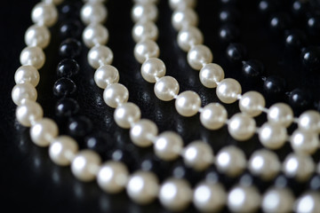 Fragment of a necklace of black and white beads on a black background close-up. Fashion background