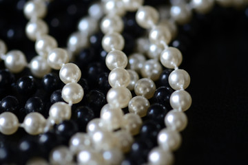 Fragment of a necklace of black and white beads on a black background close-up. Fashion background