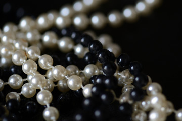 Fragment of a necklace of black and white beads on a black background close-up. Fashion background