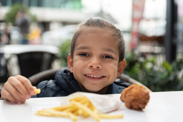 little boy eats french fries and chicken