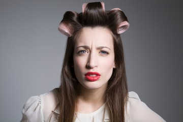 Angry Young Female With Hair Rollers Isolated Over Grey