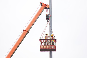 Staff with security hat on the crane lift up to fix the post