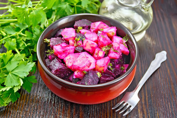 Salad of beets and potatoes with oil in bowl on table