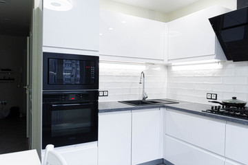 Interior of a modern white kitchen with built-in appliances. Compact minimalist kitchen.