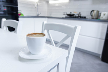 morning coffee with milk on a background of white kitchen interior.