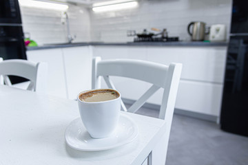 Fototapeta na wymiar morning coffee with milk on a background of white kitchen interior.