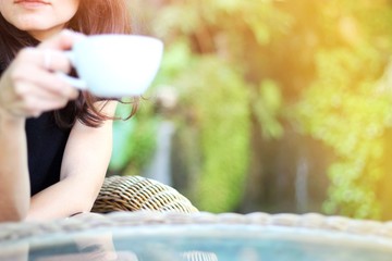 Woman holding a cup of hot americano coffee in hand, resting and relaxing times concept.