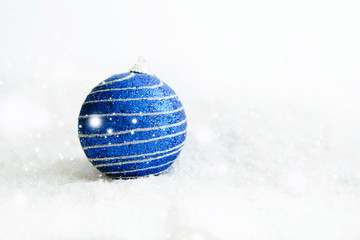 Fototapeta na wymiar Beautiful blue Christmas ball on snow Beautiful Christmas bauble decorations lie on the white fluffy snow. Atmosphere of magic and fairy tales