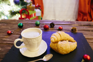 Mug with hot chocolate on a wooden table with Christmas decorations on a background of the Christmas tree