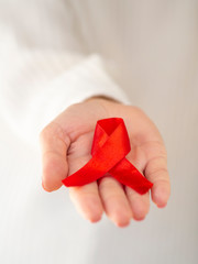 Woman in white holding red aids ribbon vertical photo