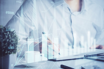Double exposure of man's hands writing notes of stock market with forex chart.