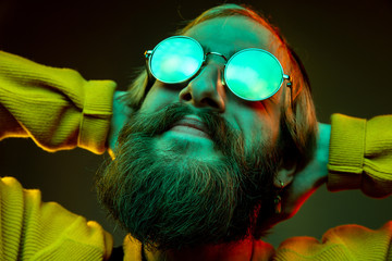 Caucasian woman's portrait on gradient studio background in neon light. Beautiful male model with hipster style in glasses. Concept of human emotions, facial expression, sales, ad. Resting, close up.