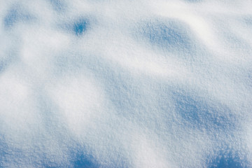 White snow texture on the sun. Winter snowy background of fresh snow with hills surface in blue tone.