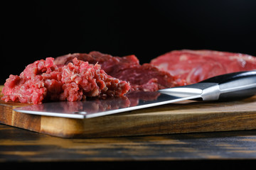 pieces of beef on a board with a knife on a black background