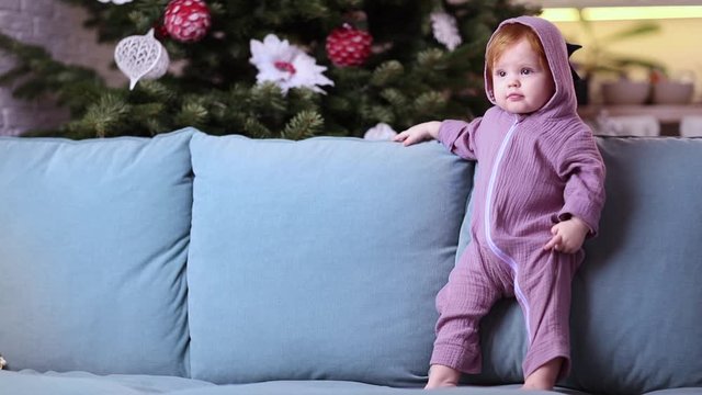 cute little baby girl in purple dinosaur romper at home in christmas time
