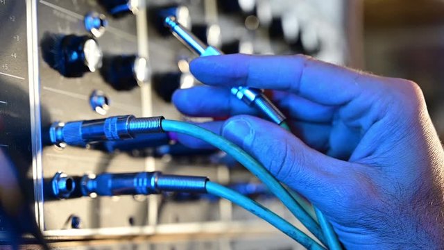 Man's hand adjusting different parameters in a music synthesizer