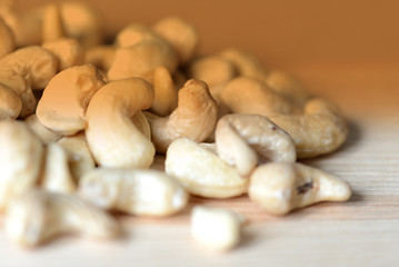 Cashew nuts scattered on a wooden surface close-up. Healthy food background. Brown color toned