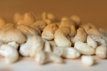 Cashew nuts scattered on a wooden surface close-up. Healthy food background. Brown color toned