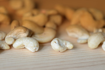 Cashew nuts scattered on a wooden surface close-up. Healthy food background. Brown color toned
