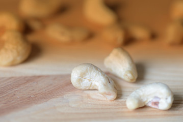 Fototapeta na wymiar Cashew nuts scattered on a wooden surface close-up. Healthy food background. Brown color toned