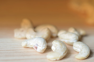 Cashew nuts scattered on a wooden surface close-up. Healthy food background. Brown color toned
