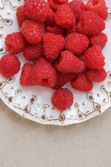 Juicy, ripe, raspberry berry on a white plate. A new harvest.