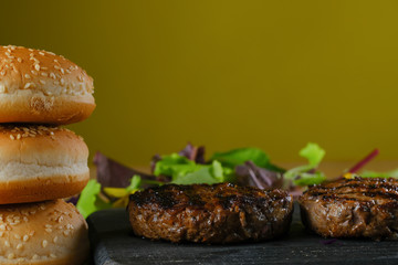 burger patties on a wooden board on a yellow background