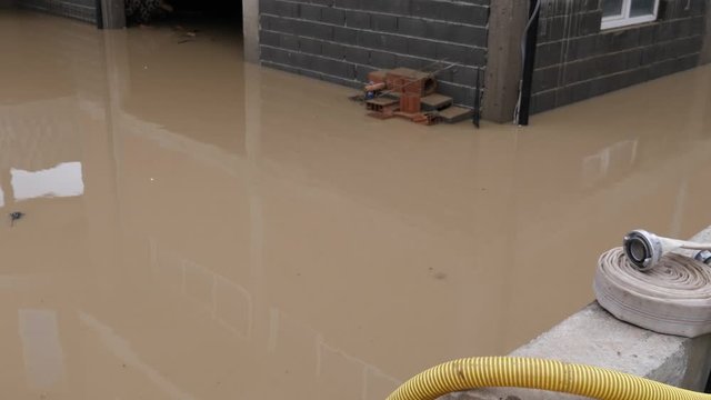 Footage of a flooded area and people pumping out water from their houses and basements