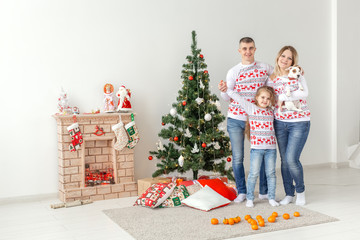 Holidays concept - happy family mother father and child at christmas tree at home