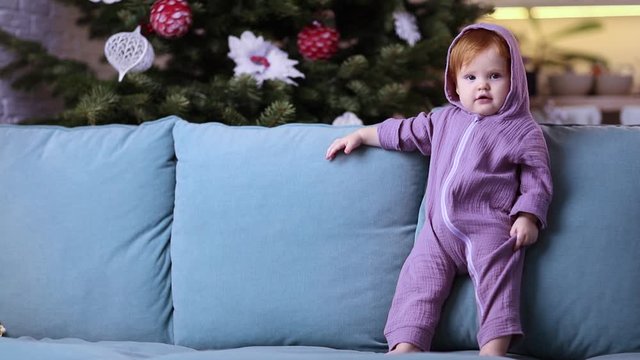 cute little baby girl in purple dinosaur romper at home in christmas time