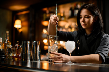 Bartender stirring ice with a bar spoon - obrazy, fototapety, plakaty