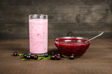 Glass of yoghurt cocktail, smoothies, with raspberries, with jam stands on a birch stump, on wood background.