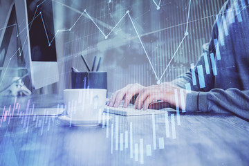 Multi exposure of graph with man typing on computer in office on background. Concept of hard work.