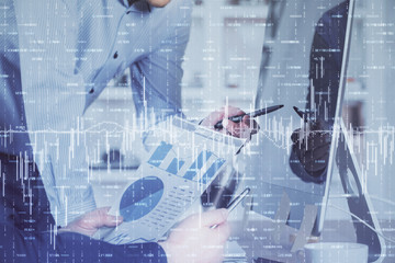 Double exposure of chart with businessman typing on computer in office on background. Concept of hard work.